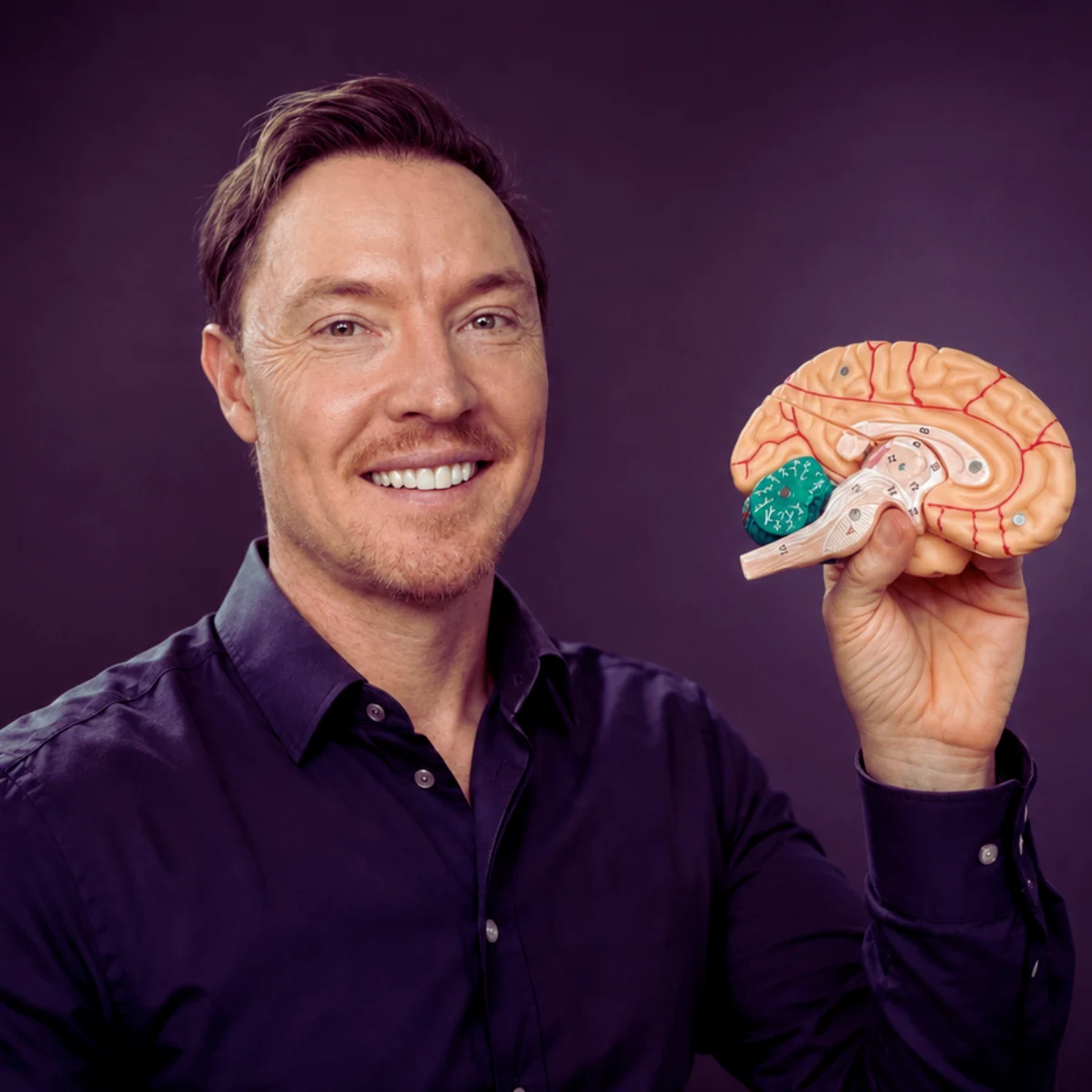 Bradley Hook, founder of the Values Institute, smiling and holding a model of the human brain